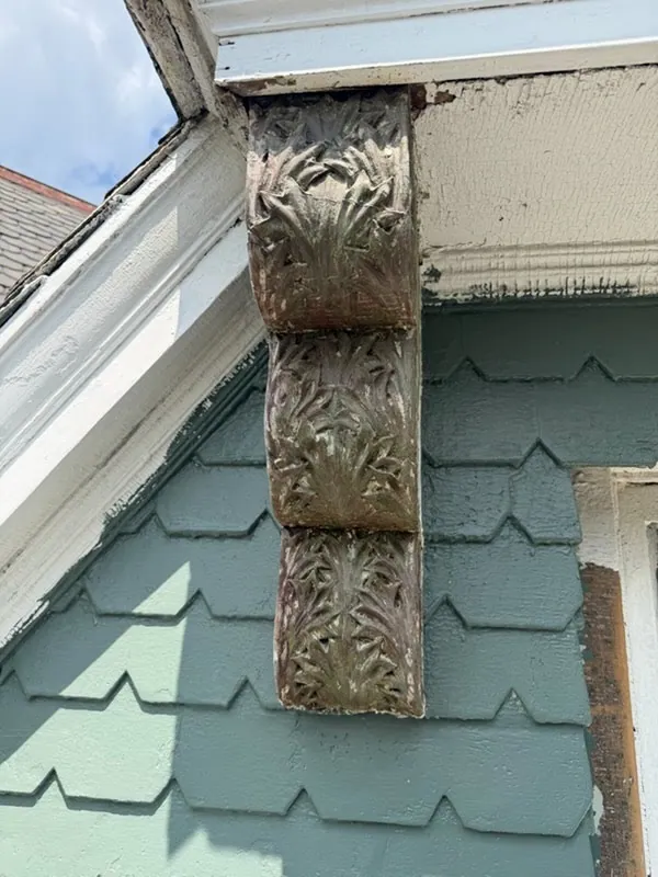 The same bracket stripped to bare wood: three tiers of carved acanthus leaves with traces of old paint.