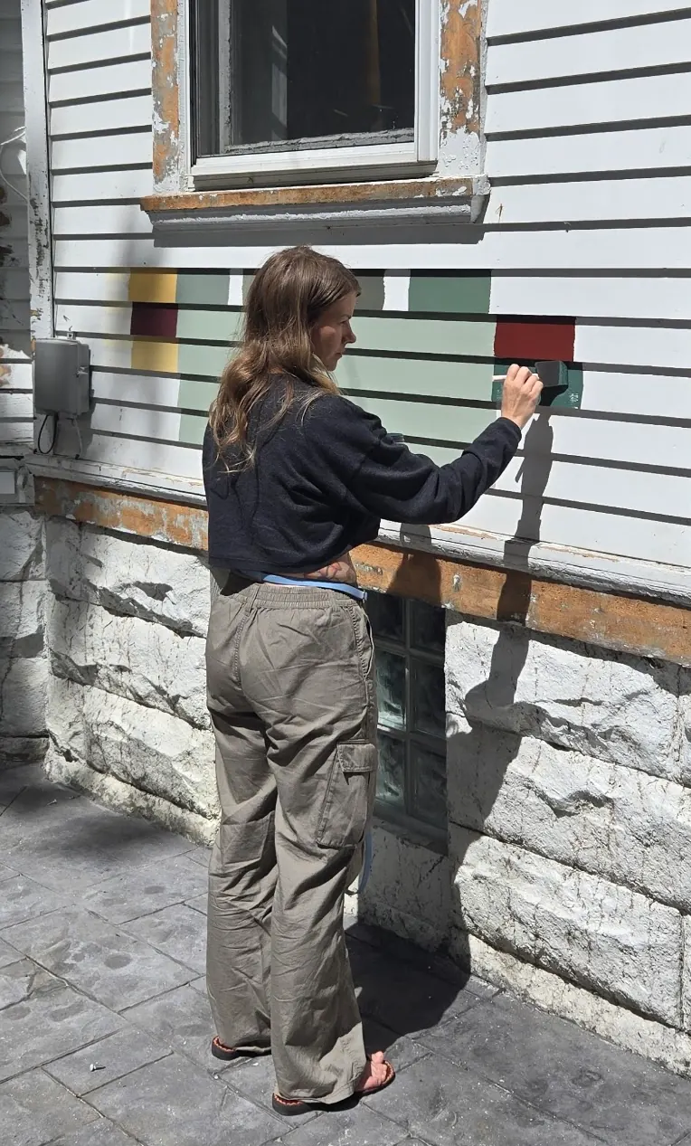 Samples of burgundy, sage, green and gold painted on the siding while one of us adds another swatch.